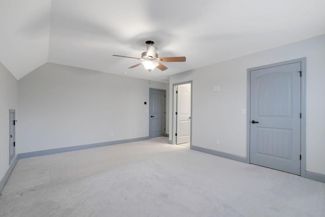 empty room featuring ceiling fan, light colored carpet, and vaulted ceiling