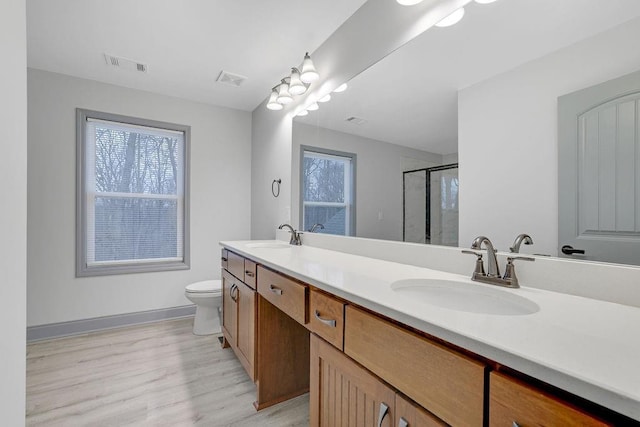 bathroom featuring a shower with door, vanity, hardwood / wood-style floors, and toilet