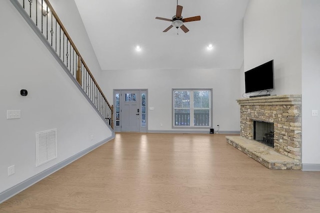 unfurnished living room featuring a fireplace, light wood-type flooring, high vaulted ceiling, and ceiling fan