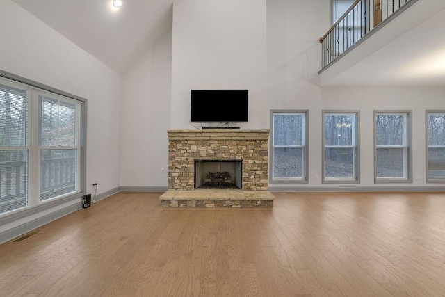 unfurnished living room featuring a fireplace, high vaulted ceiling, and light hardwood / wood-style flooring