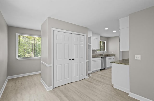 1819 Laurel Ridge Dr SW, Conyers, GA 30094 - kitchen with stainless steel dishwasher, white cabinetry, light wood-style flooring, baseboards, and plenty of natural light