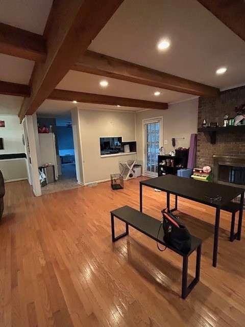 recreation room with a brick fireplace, beamed ceiling, and hardwood / wood-style floors