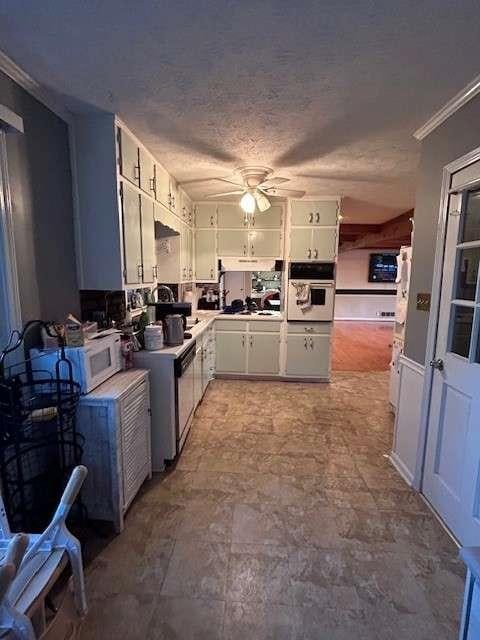 kitchen featuring oven, ceiling fan, a textured ceiling, and white cabinetry