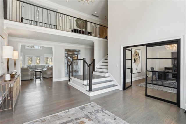 entryway with stairway, a high ceiling, wood finished floors, and crown molding