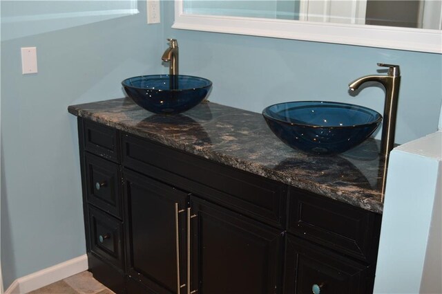 full bath with baseboards, a sink, and double vanity