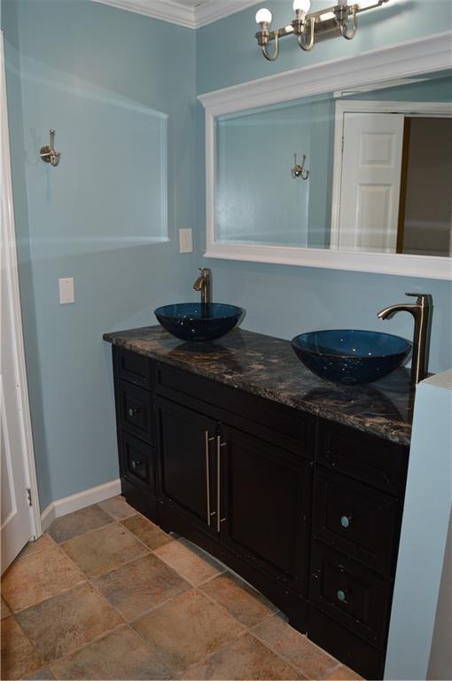bathroom featuring stone finish floor, a sink, a chandelier, and ornamental molding