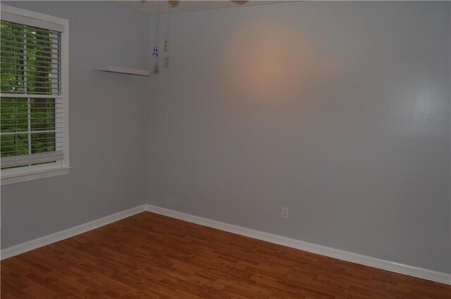 unfurnished room with baseboards and wood finished floors