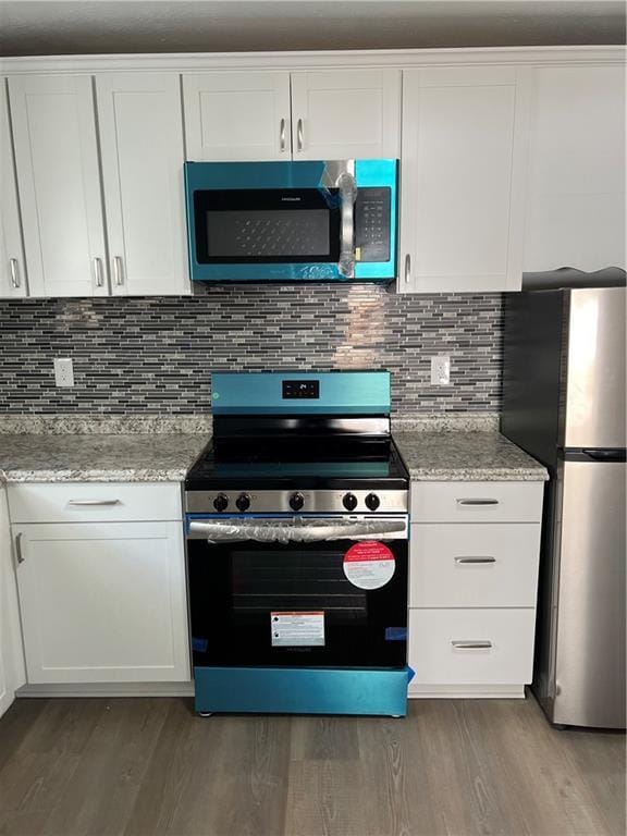 kitchen with white cabinetry, backsplash, dark hardwood / wood-style flooring, light stone counters, and stainless steel appliances