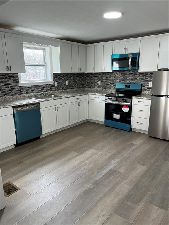 kitchen featuring appliances with stainless steel finishes, sink, light hardwood / wood-style floors, and white cabinets