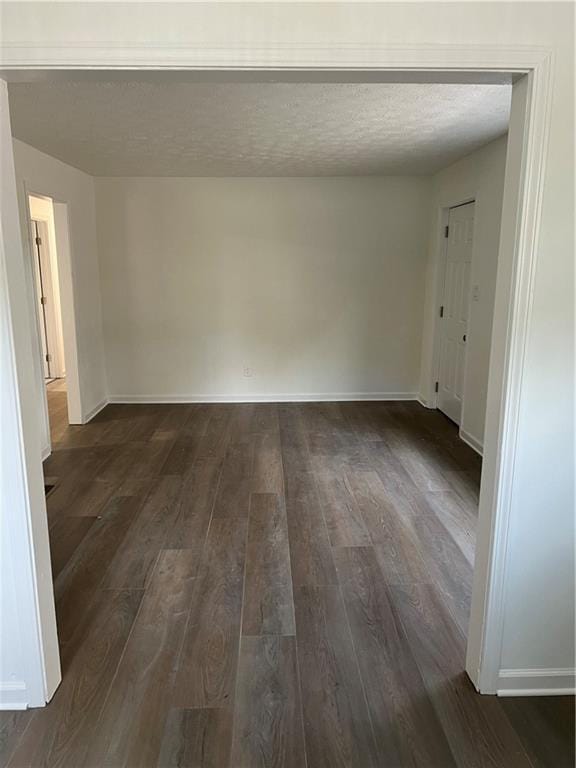 empty room featuring dark wood-type flooring and a textured ceiling