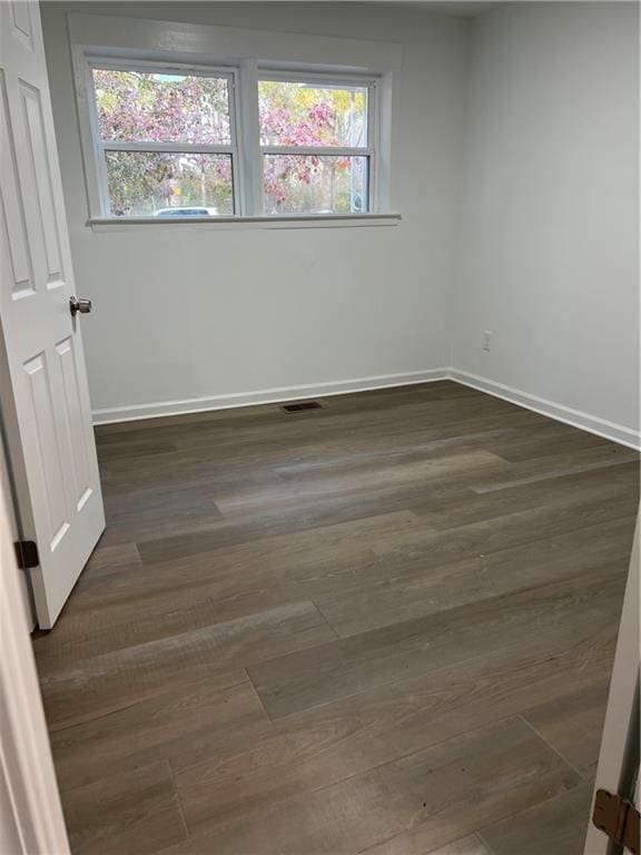 empty room with dark hardwood / wood-style floors and a wealth of natural light