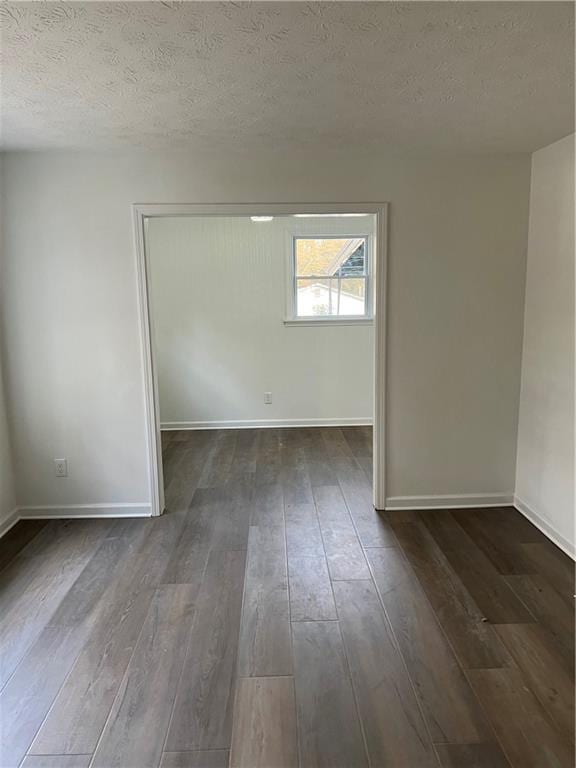 unfurnished room with dark hardwood / wood-style floors and a textured ceiling