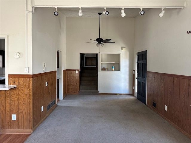 2195 Wilson Rd, Conyers, GA 30012 - unfurnished living room featuring rail lighting, a high ceiling, a wainscoted wall, wood walls, and ceiling fan