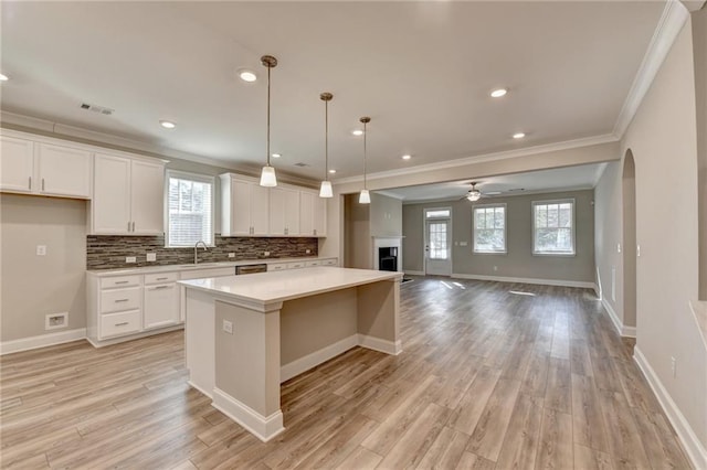 kitchen with pendant lighting, sink, white cabinetry, tasteful backsplash, and a kitchen island