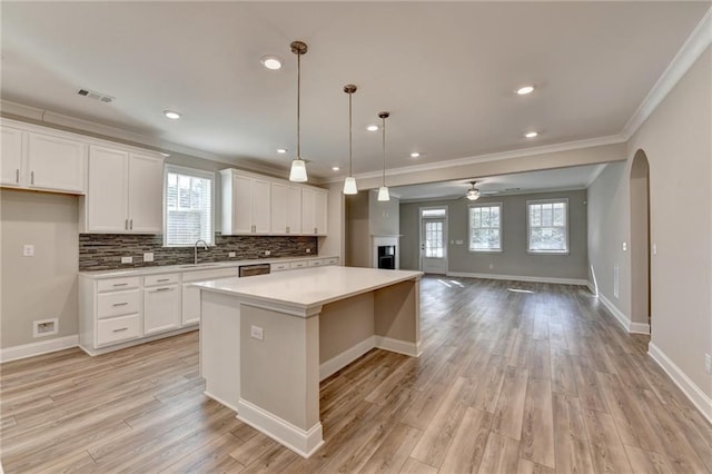 kitchen with sink, white cabinetry, decorative backsplash, a kitchen island, and decorative light fixtures