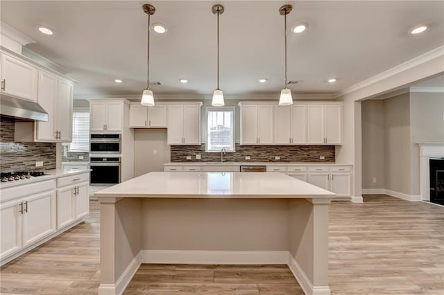 kitchen with stainless steel double oven, decorative light fixtures, and a kitchen island