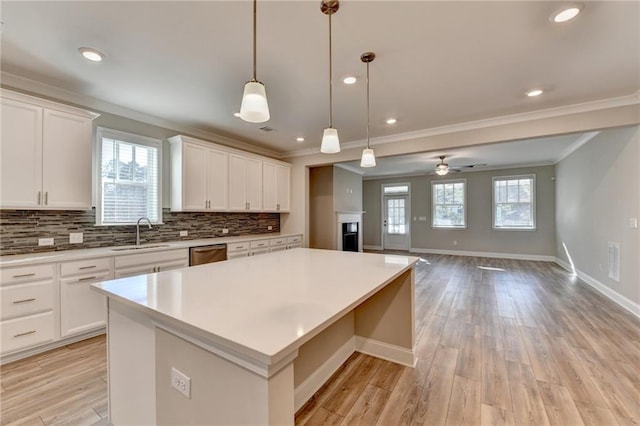 kitchen featuring sink, dishwasher, white cabinetry, hanging light fixtures, and a center island