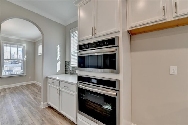 kitchen featuring a healthy amount of sunlight, ornamental molding, and white cabinets