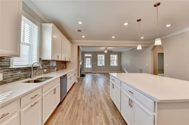 kitchen with sink, a center island, hanging light fixtures, stainless steel dishwasher, and white cabinets