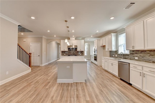 kitchen with white cabinetry, a center island, hanging light fixtures, light wood-type flooring, and appliances with stainless steel finishes