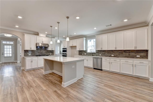 kitchen featuring decorative light fixtures, light hardwood / wood-style flooring, appliances with stainless steel finishes, a kitchen island, and white cabinets