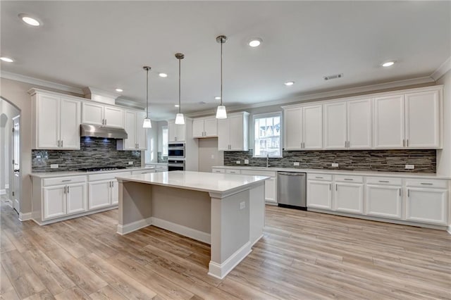 kitchen featuring pendant lighting, appliances with stainless steel finishes, white cabinetry, ornamental molding, and a kitchen island