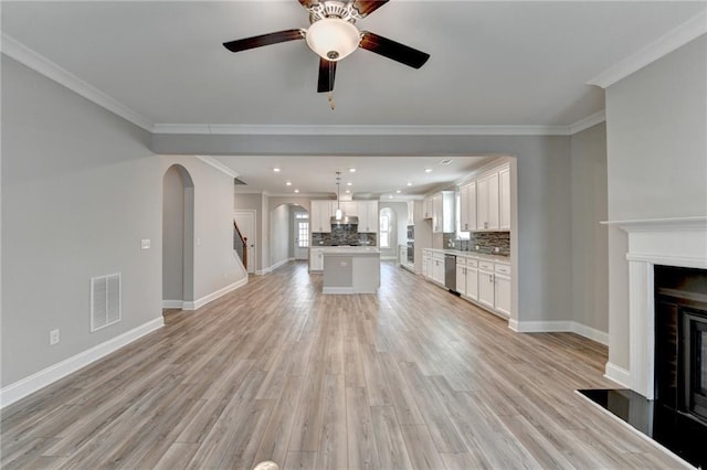 unfurnished living room with crown molding, ceiling fan, and light hardwood / wood-style flooring