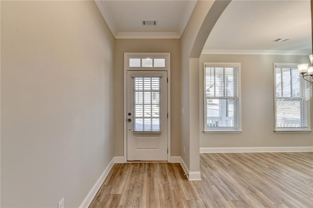 doorway with ornamental molding, a chandelier, a wealth of natural light, and light wood-type flooring