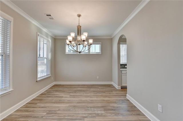 unfurnished dining area featuring an inviting chandelier, crown molding, and light hardwood / wood-style floors