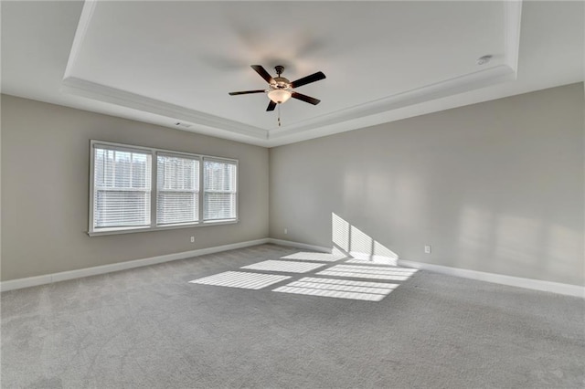 carpeted spare room featuring a raised ceiling and ceiling fan