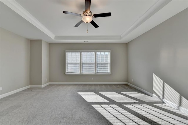 spare room featuring light colored carpet, ceiling fan, and a tray ceiling