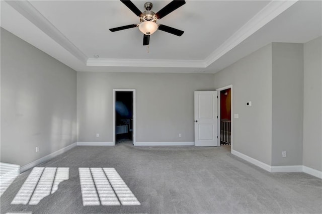 carpeted spare room with ceiling fan, ornamental molding, and a tray ceiling