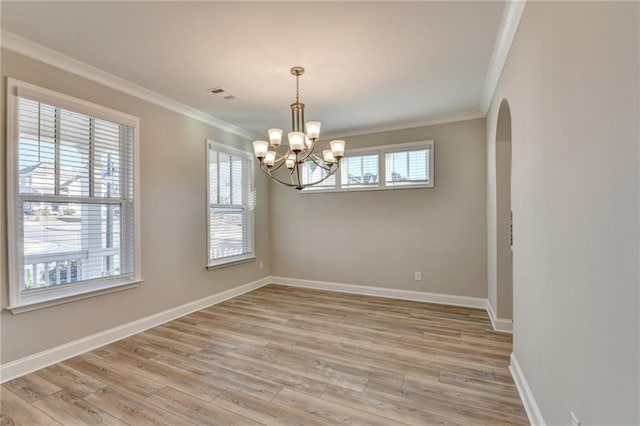 spare room featuring an inviting chandelier, ornamental molding, and light hardwood / wood-style floors