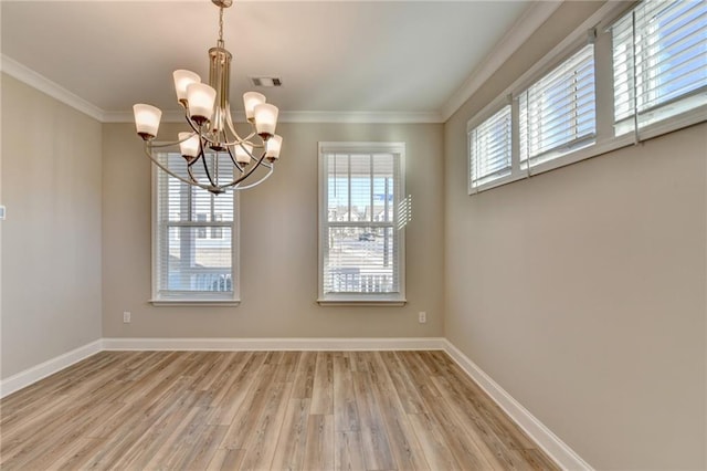 unfurnished dining area with ornamental molding, a chandelier, and light wood-type flooring