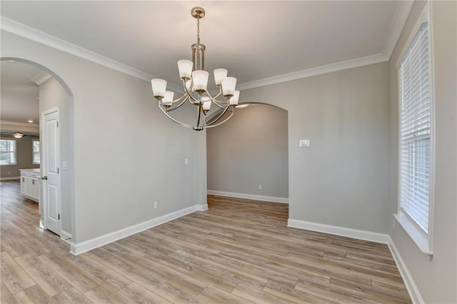 empty room featuring ornamental molding, a chandelier, and light wood-type flooring