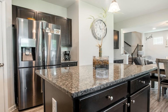 kitchen featuring light hardwood / wood-style floors, dark stone counters, a kitchen island, and stainless steel fridge with ice dispenser