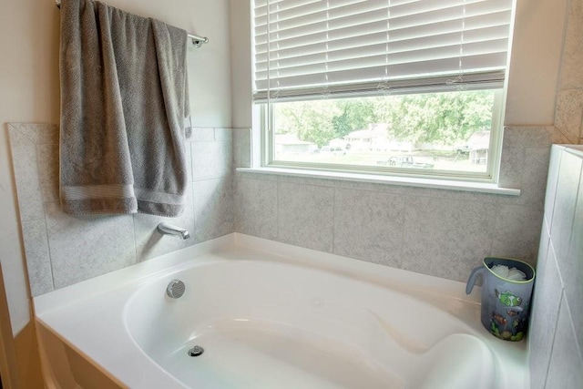 bathroom featuring a bathing tub, plenty of natural light, and tile walls