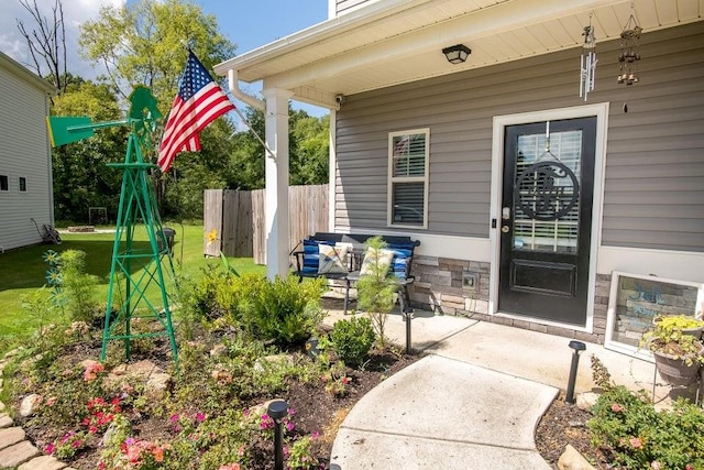 entrance to property featuring a patio and a lawn