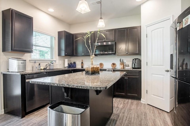 kitchen featuring stainless steel appliances, dark brown cabinetry, a kitchen island, pendant lighting, and light wood-type flooring