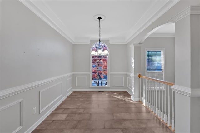 unfurnished dining area featuring a wealth of natural light, a decorative wall, arched walkways, and an inviting chandelier