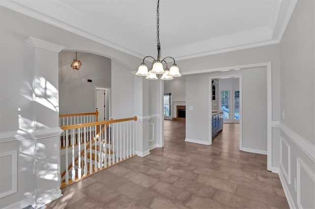 hall featuring baseboards, arched walkways, ornamental molding, an upstairs landing, and a notable chandelier