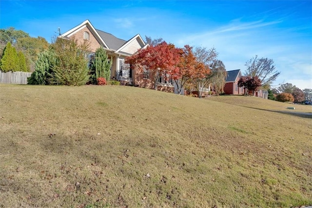 view of property hidden behind natural elements with fence and a front lawn