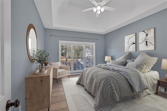 bedroom with a raised ceiling and a ceiling fan