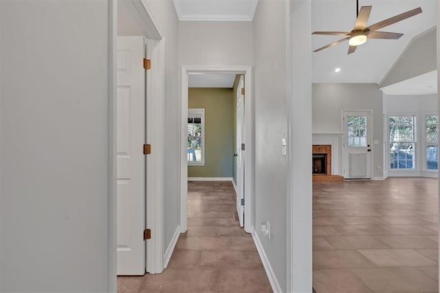 hallway featuring vaulted ceiling, ornamental molding, plenty of natural light, and baseboards