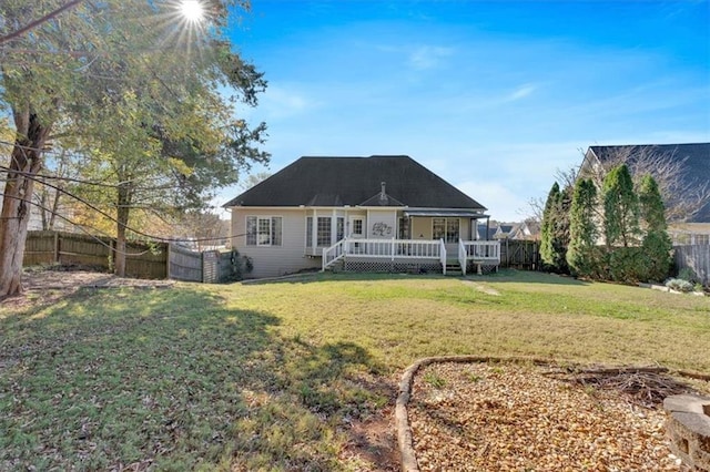 rear view of property featuring a deck, a yard, and a fenced backyard