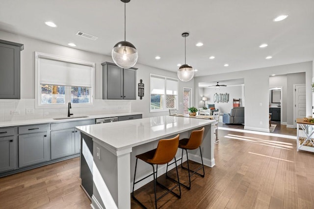 kitchen featuring gray cabinets, visible vents, a kitchen island, a sink, and wood finished floors