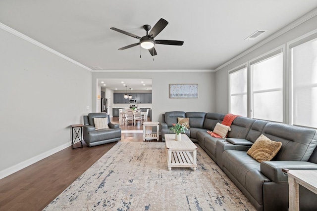 living area with baseboards, visible vents, crown molding, and wood finished floors