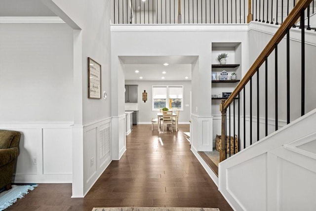 entryway featuring stairs, a high ceiling, dark wood-style flooring, and a decorative wall