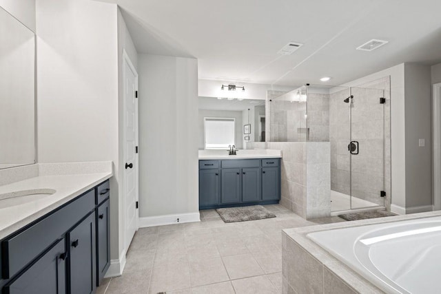 full bath with a stall shower, two vanities, a sink, and a garden tub