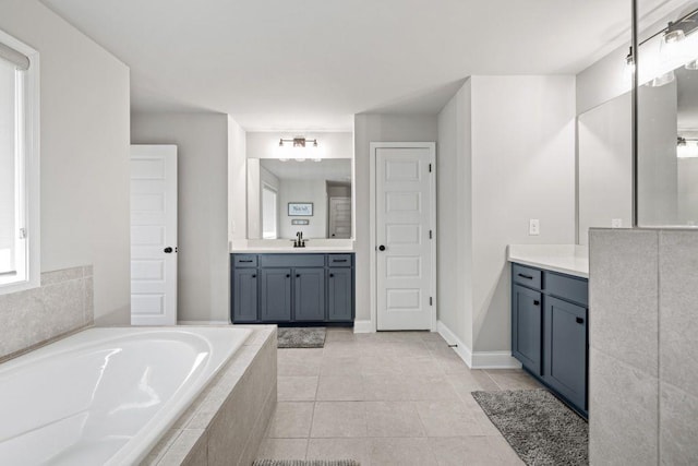 bathroom with baseboards, vanity, a bath, and tile patterned floors